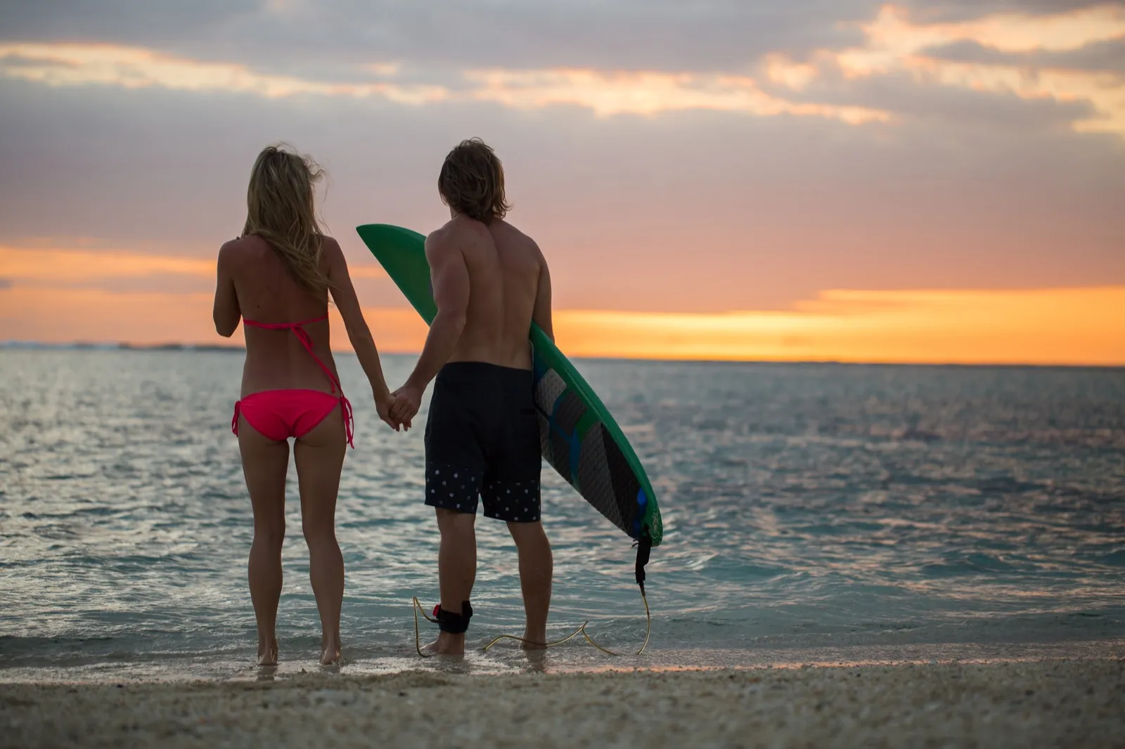 Couple with surfboards watching sunset on Miami Beach