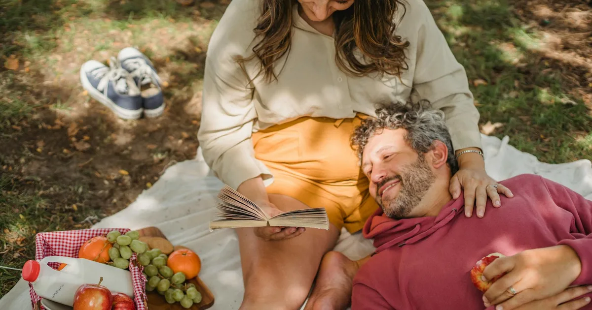 Romantic sunset picnic anniversary date with couple enjoying wine and food outdoors