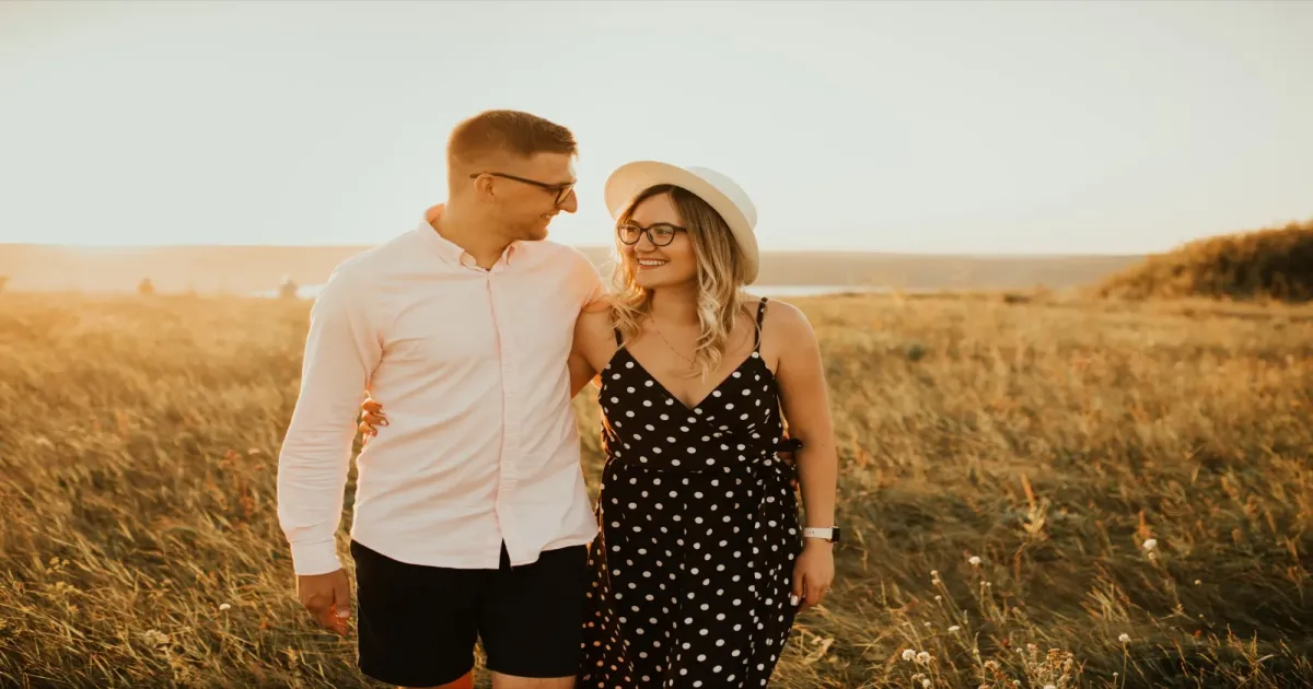 Couple walking together through a sunny field holding hands