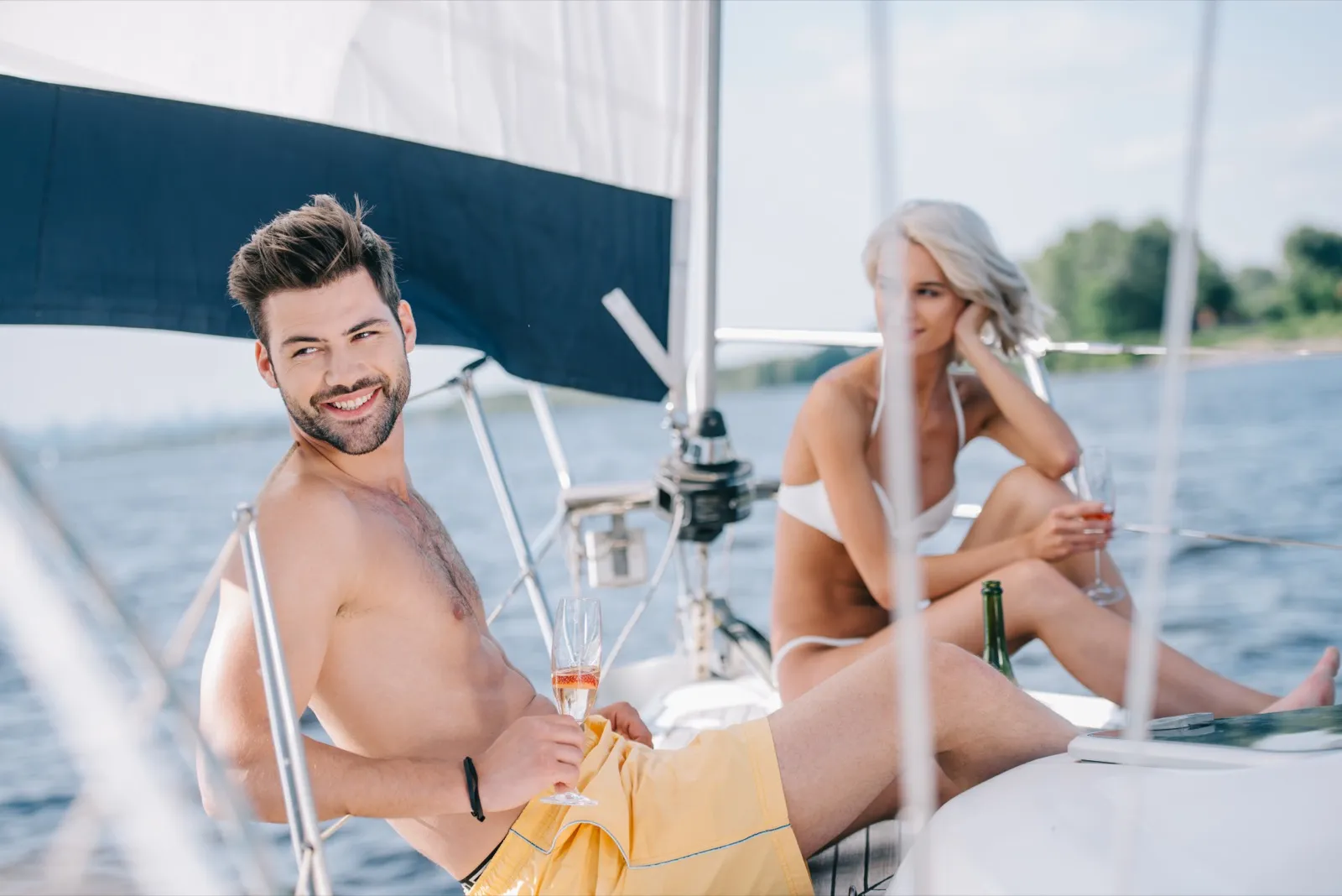 Couple clinking champagne glasses on a sunset sailboat in San Diego Bay