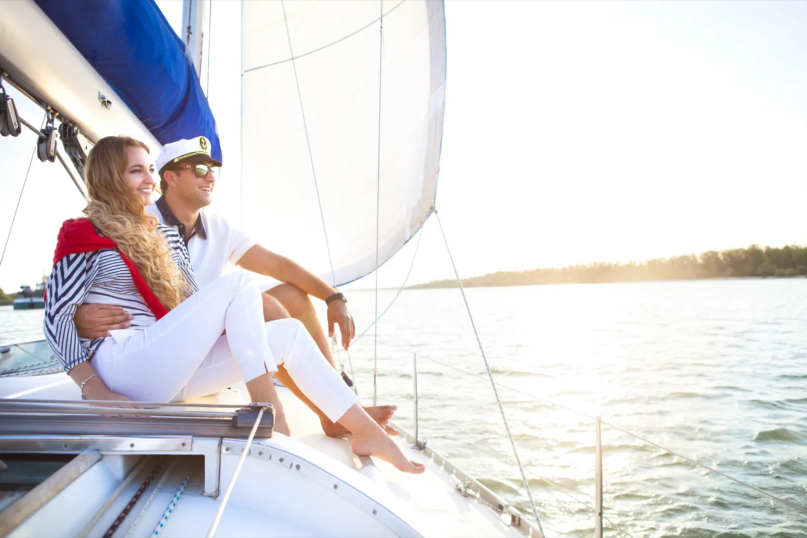 Young couple smiling on a sailboat in New York Harbor with the Manhattan skyline behind them