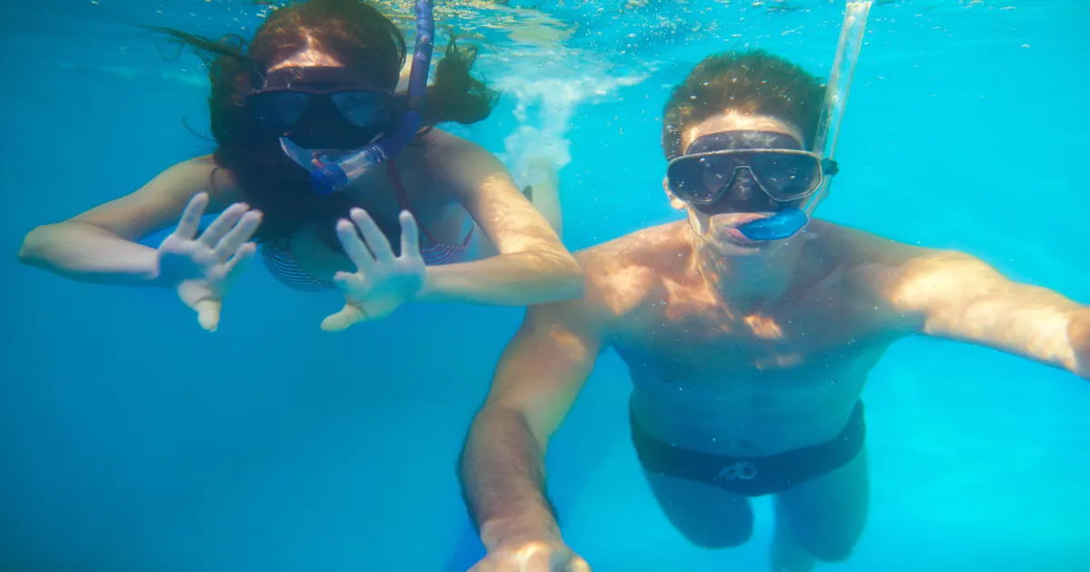 Couple swimming underwater near green sea turtles off the coast of Oahu