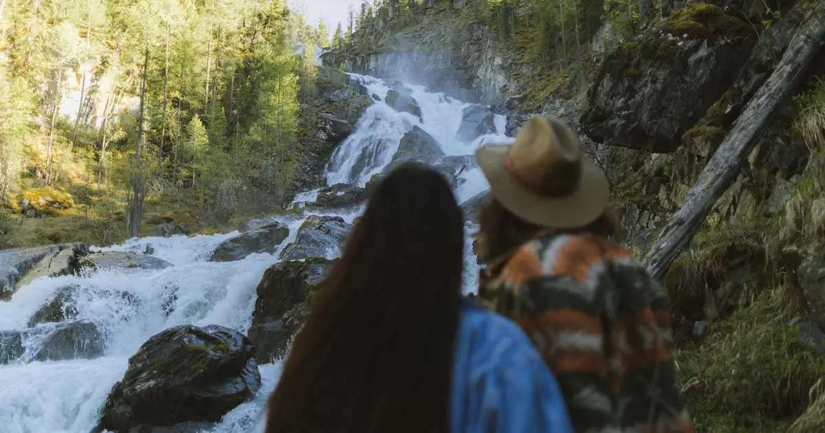 Couple standing in front of Manoa Falls waterfall surrounded by tropical rainforest