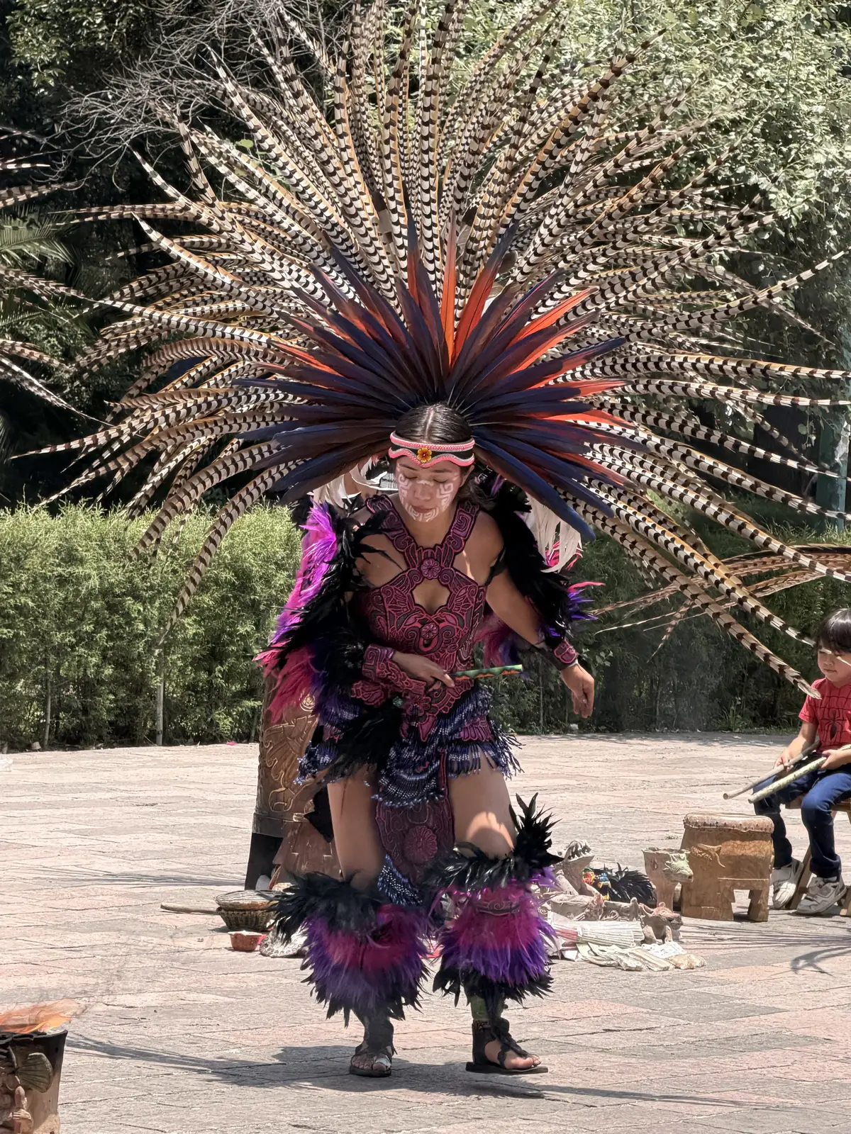 A Mexica dancer in a large feathered headdress performing on the plaza outside the anthropology museum