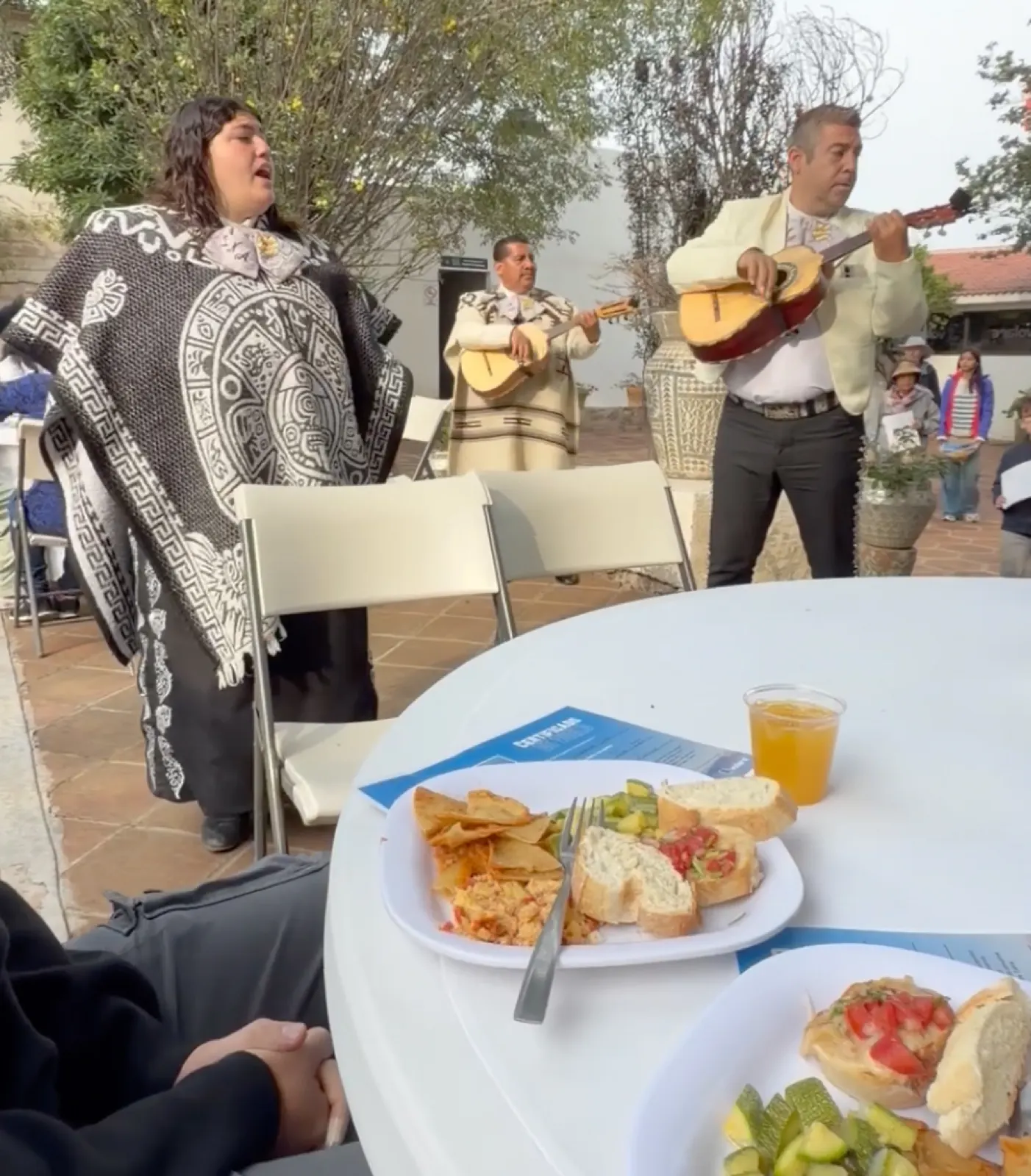 A mariachi trio playing beside an outdoor table set with breakfast plates and juice after a balloon flight