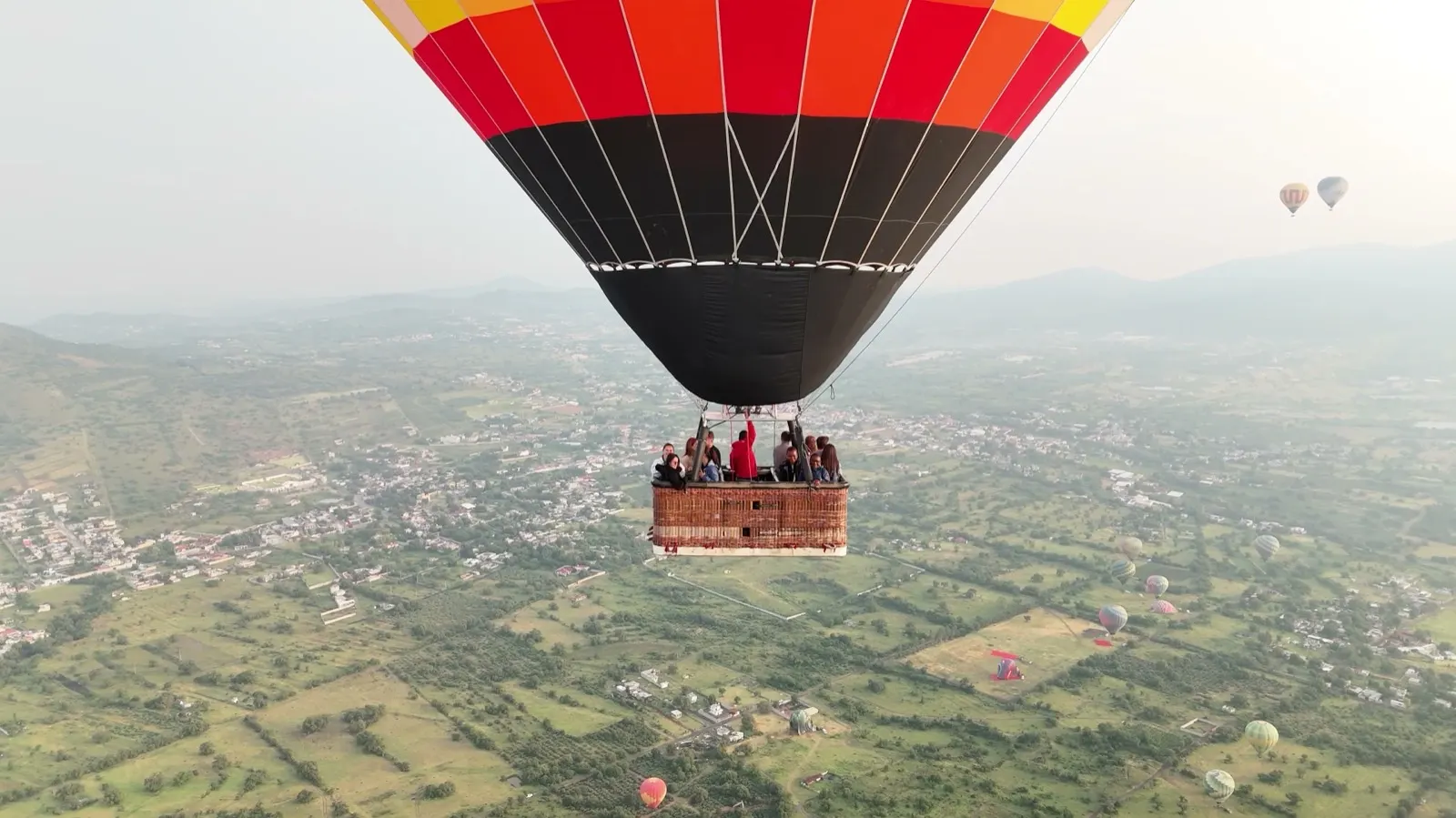 Hot air balloon full of passengers seen from a drone over the Teotihuacan valley