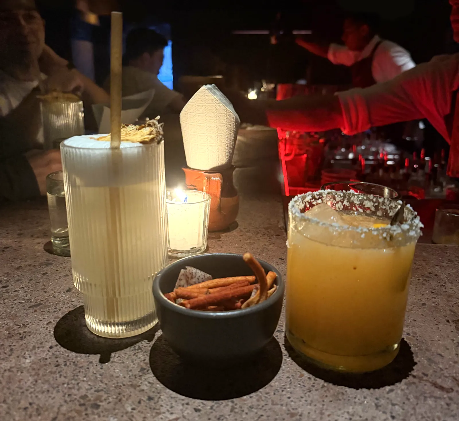 Two cocktails and a bowl of snacks on a bar counter in Mexico City at night