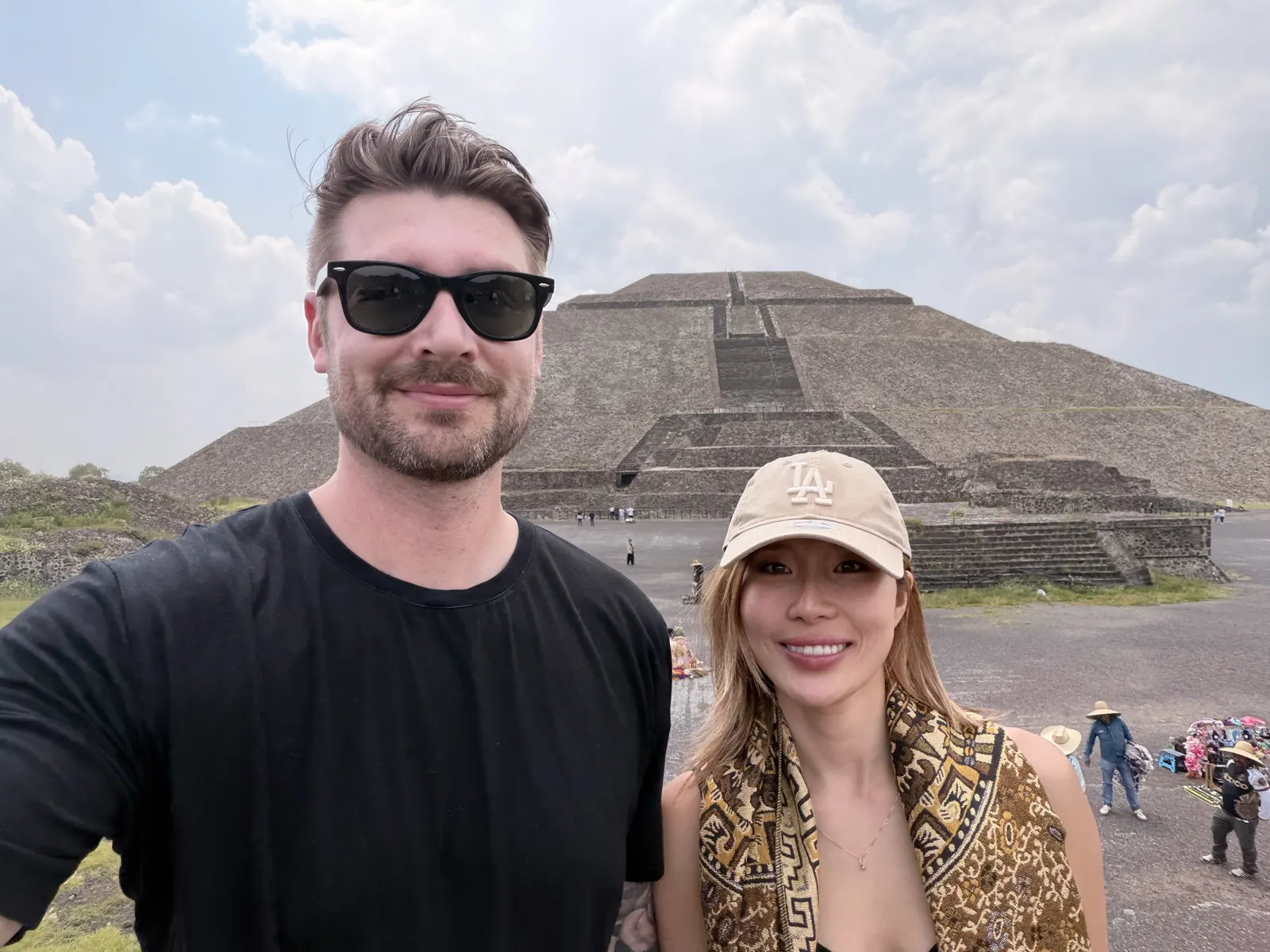Couple standing in front of one of the Teotihuacan pyramids on a bright cloudy day
