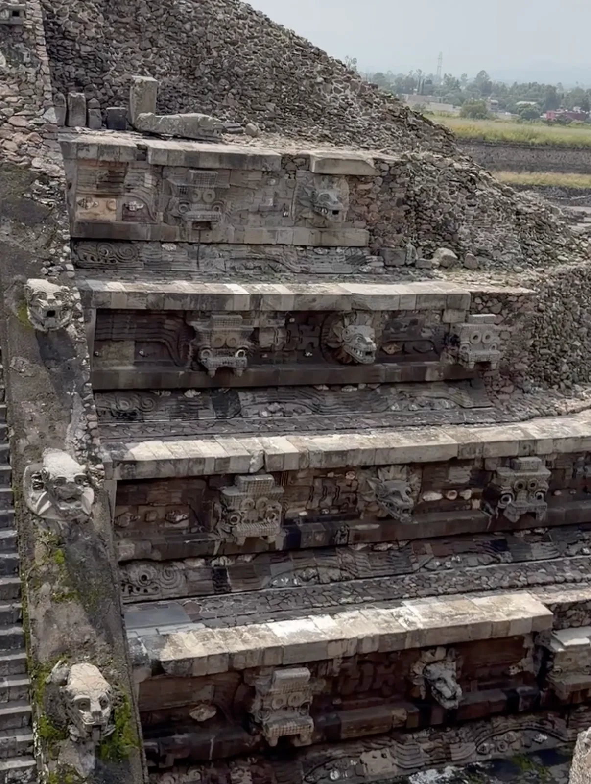 Carved serpent heads and stone masks along the terraced facade of the Temple of the Feathered Serpent at Teotihuacan