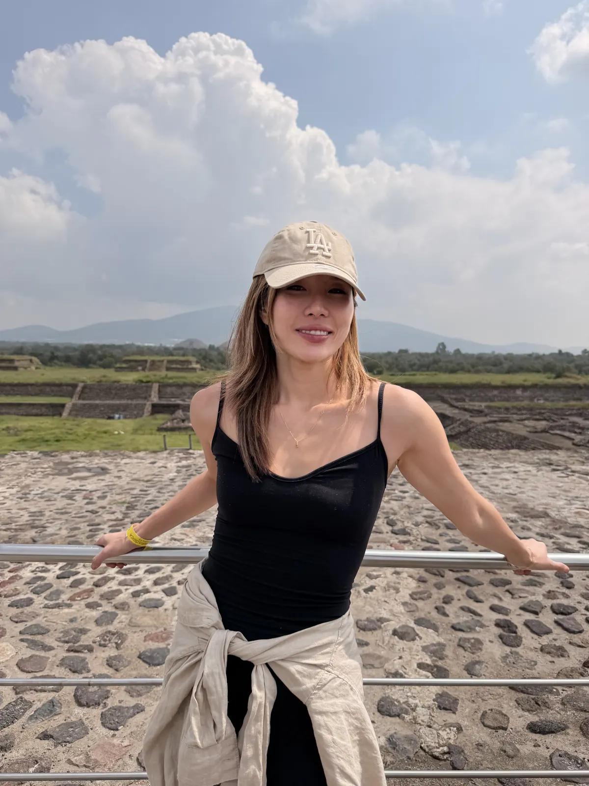 Woman standing on a stone platform among the Teotihuacan ruins with storm clouds behind